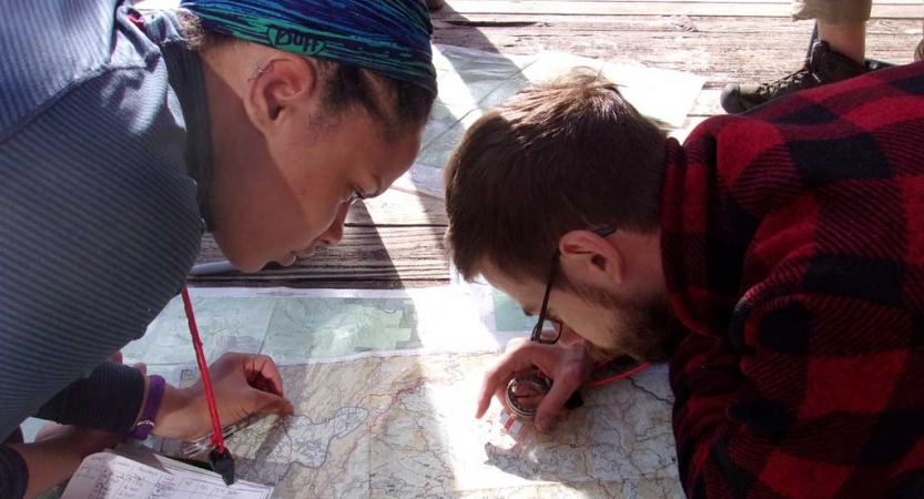 Two people lean forward over a map as they examine it closely. 